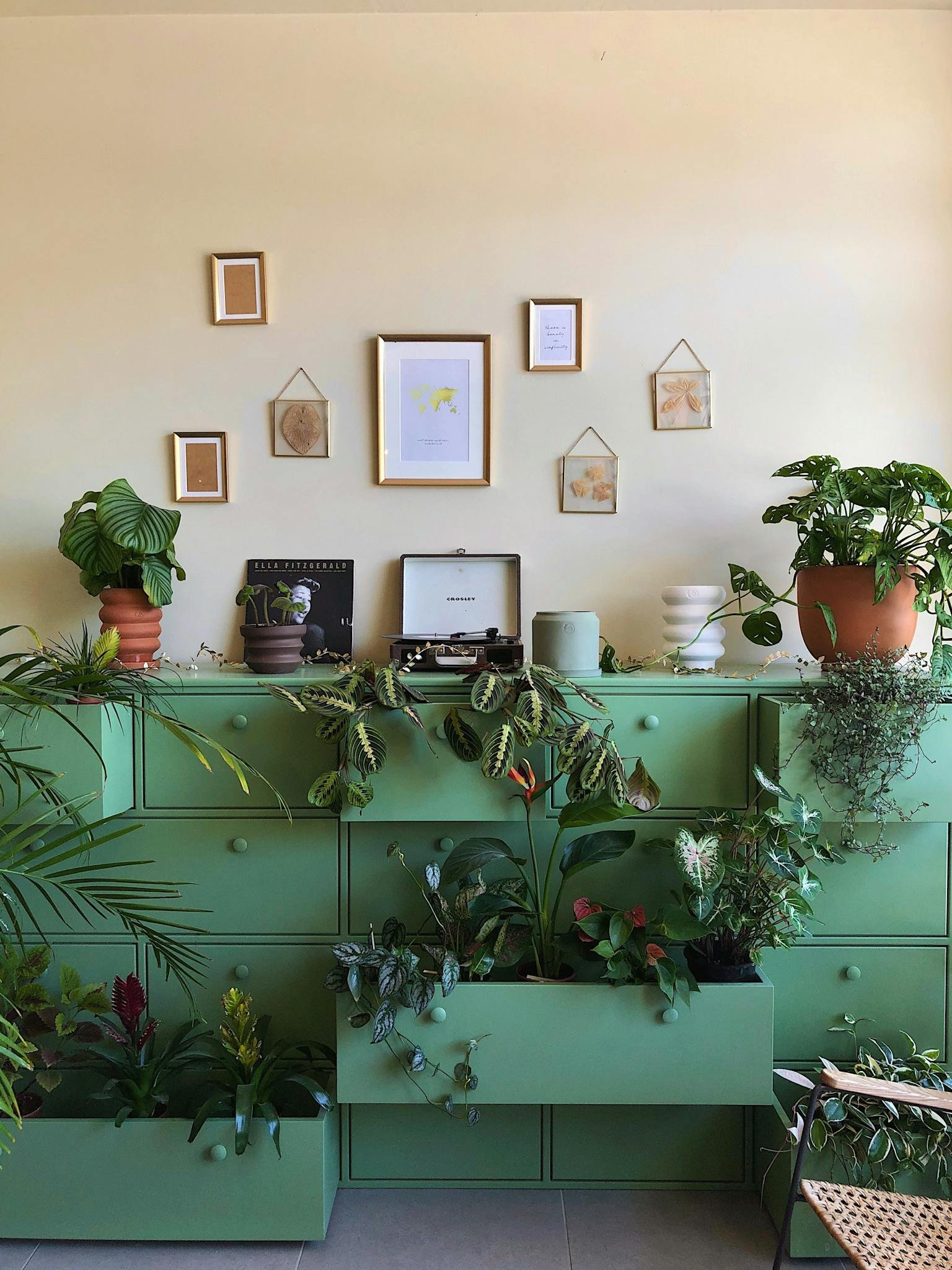 Decorative green cupboard with potted plants and framed art in a cozy interior.
